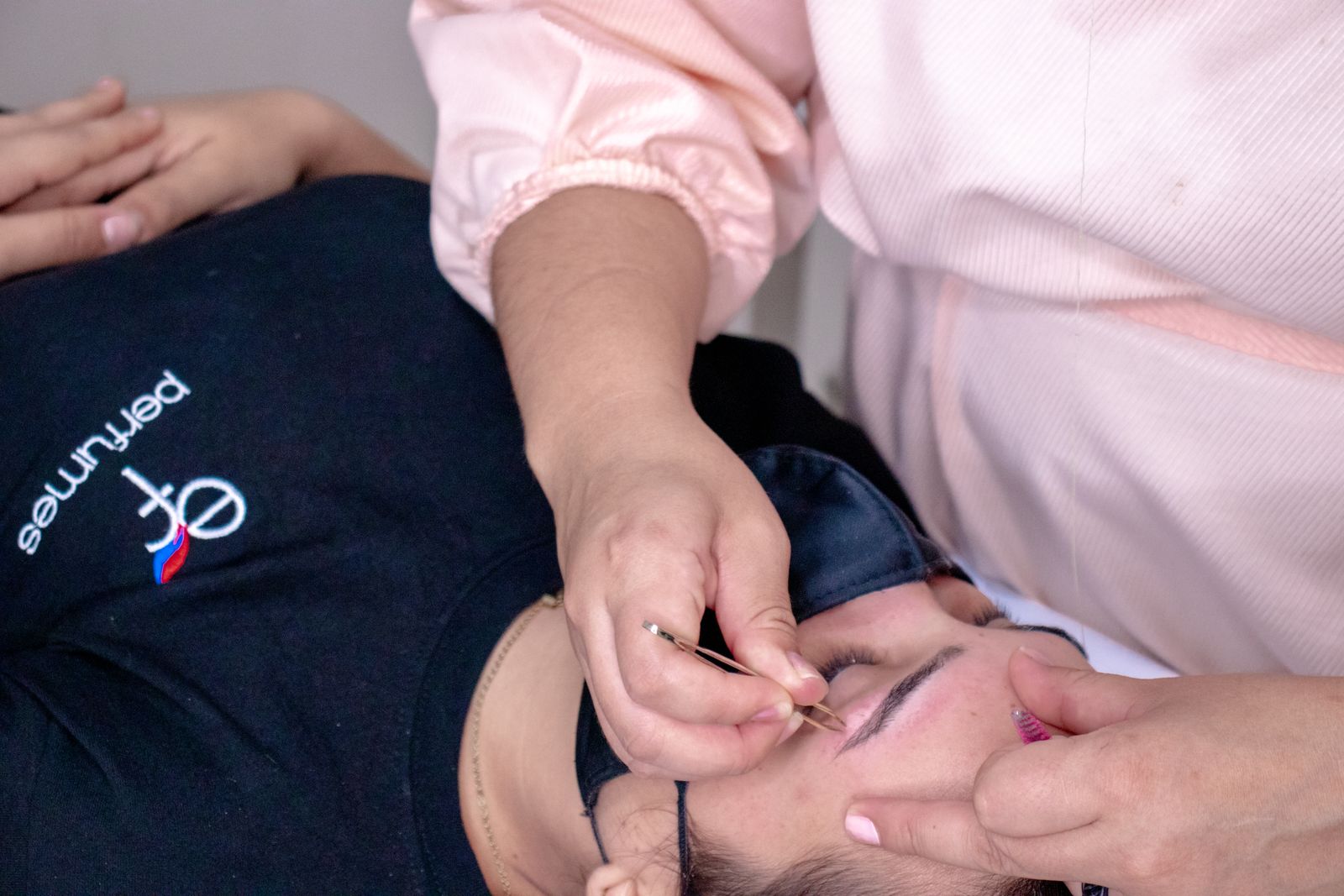 Close-up of a spa technician plucking eyebrows during a facial treatment, highlighting beauty care.